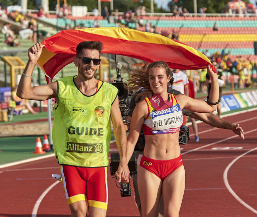 Lia portando la bandera junto a su guía / Patrocina a un Deportista