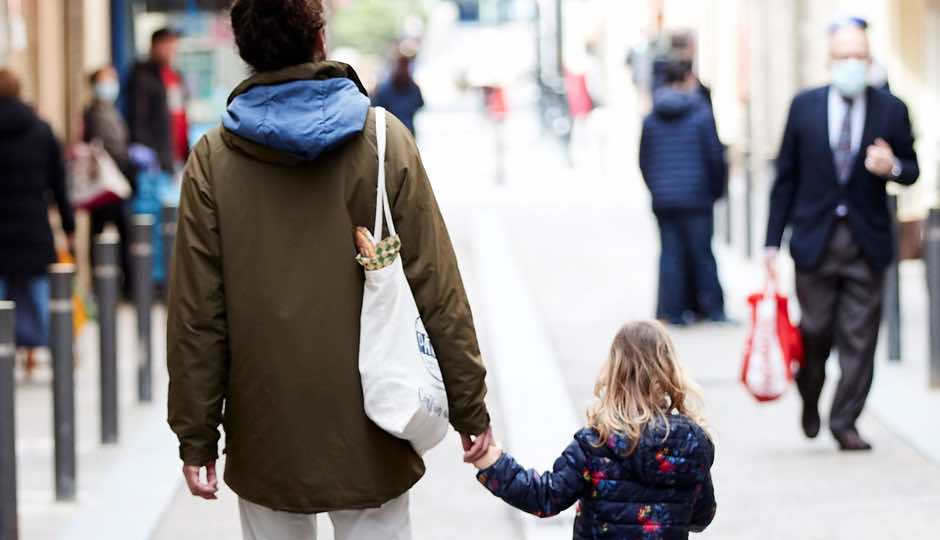 Niña de la mano de su padre por la calle