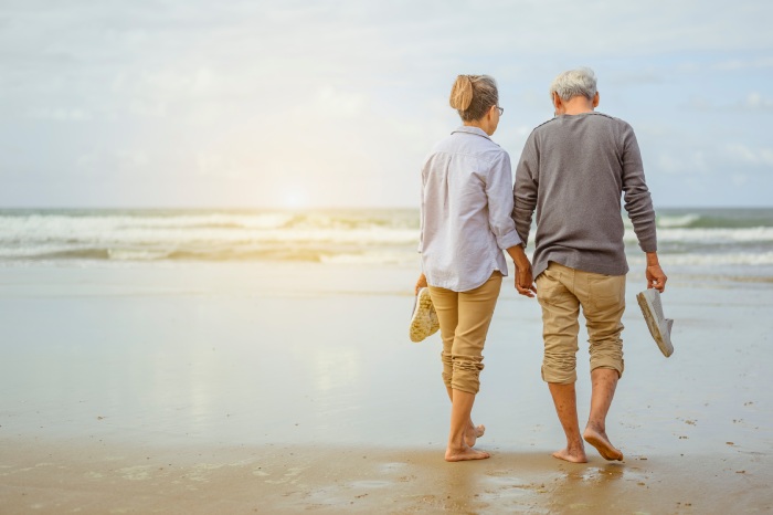 dos personas jubiladas paseando por la playa