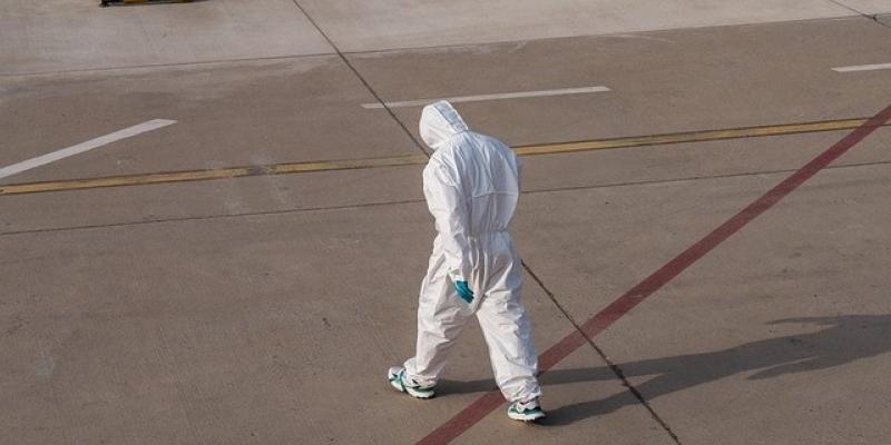 Un sanitario cabizbajo camina hacia el hospital con un traje EPI