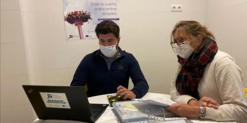 Arrabal autoempleo / Arrabal-AID Sesión personalizada para favorecer el autoempleo. En la imagen dos personas con mascarilla revisan una documentación con un portátil abierto