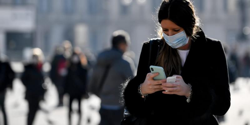 Los bulos y mensajes con rumores sobre el coronavirus invaden nuestros teléfonos Mujer mirando un mensaje con mascarilla