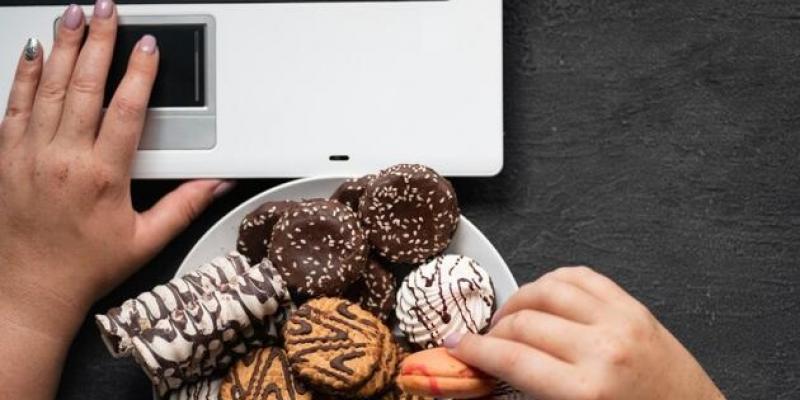 Trastorno por atracón - Pixabay Una persona utiliza su ordenador con un plato de galletas al lado