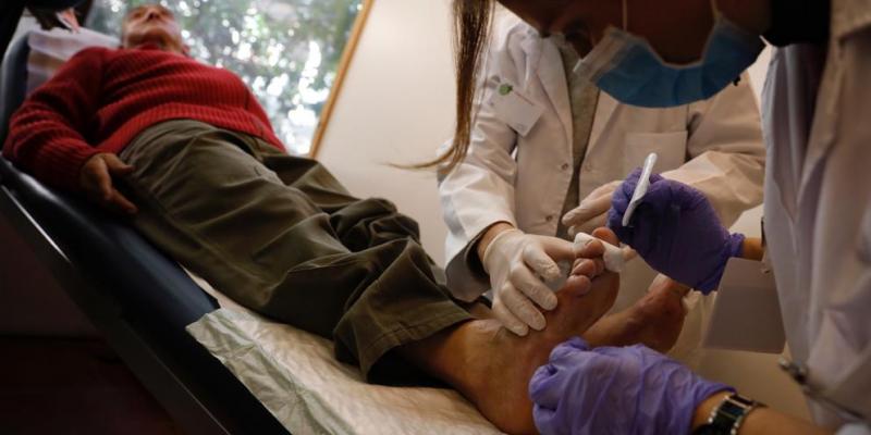 Profesionales atendiendo a una persona sin hogar en el servicio de podología Hospital Sagrado Corazón Barcelona Parroquia