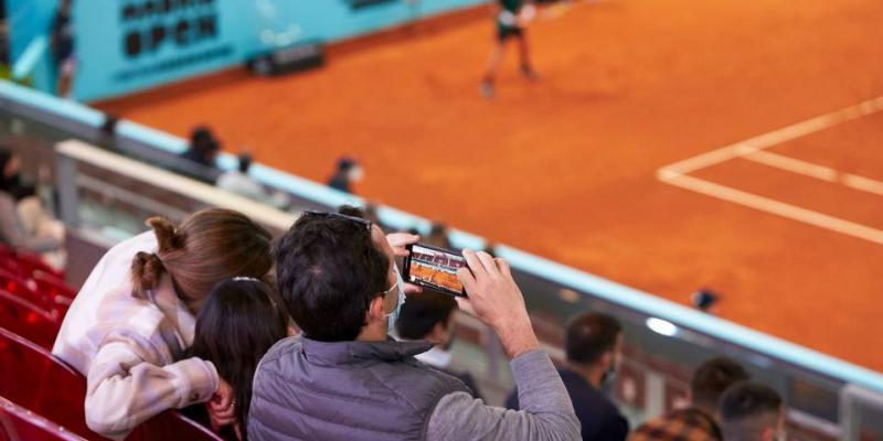 Espectador disfrutando de un partido de la Mutua Madrid Open- Archivo fotográfico MMO Un espectador de la Muta Madrid Open hace una fotografía del terreno de juego
