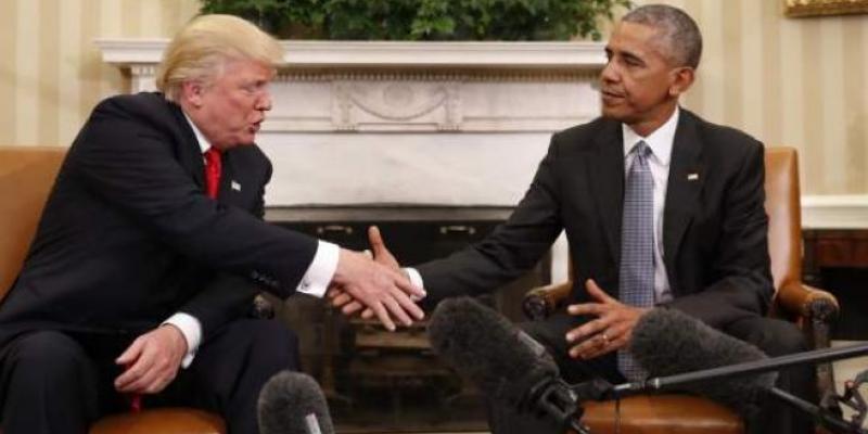Trump a la izquierda y Obama a la derecha ambos sentados y se dan la mano.