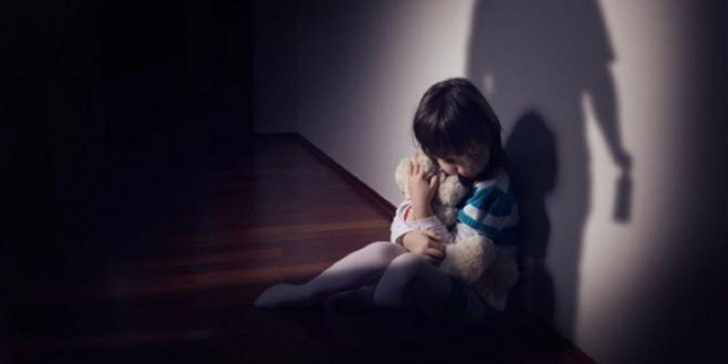 Niño en una casa oscura con la sombra de un adulto