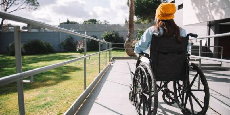 Una persona en silla de ruedas baja por una rampa | Foto de 123RF/javierlarraondo
