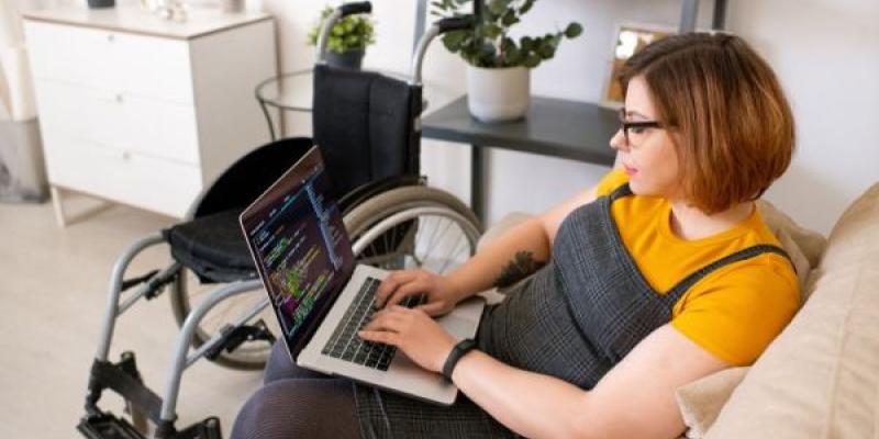 Una mujer con discapacidad programa diseño web en su ordenador