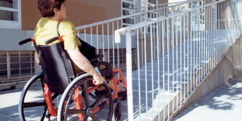 Una mujer en silla de ruedas accede al portal de un edificio de viviendas./ ONCE Una mujer en silla de ruedas accede al portal de un edificio de viviendas.