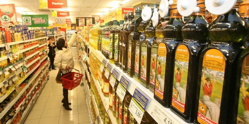 Estanterías de aceite en supermercado / Imagen de El Periódico Señora comprando aceite en un supermercado