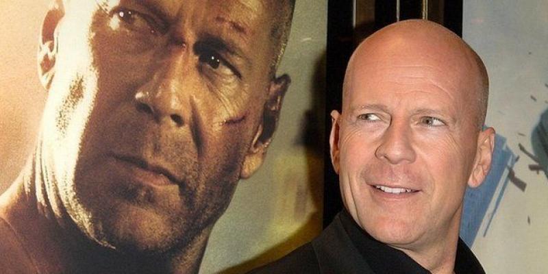 Bruce Willis posa junto al cartel de una de sus películas