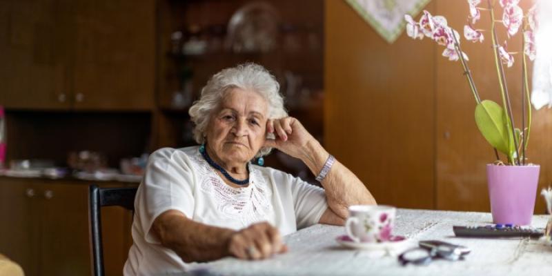 Soledad de las personas mayores | Foto de 123RF/piksel Una mujer mayor sentada junto a la mesa de su casa