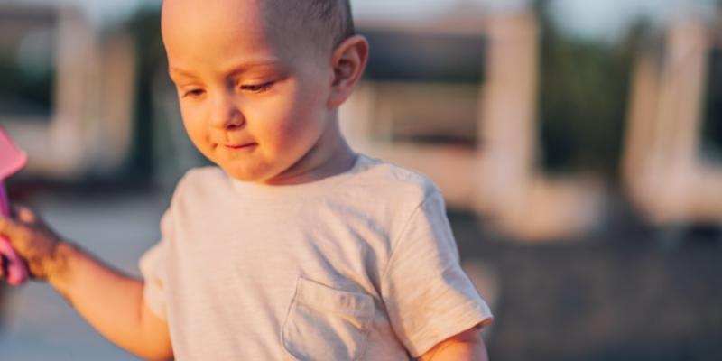 Cáncer infantil - Foto: Envato Elements Un niño caucásico de pie en la playa soleada y mirando hacia abajo