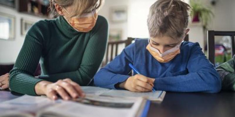 Bajas médicas: una madre con su hijo estudiando en casa