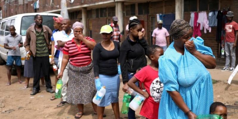 Personas en África hacen una cola con las mascarillas en sus rostros 