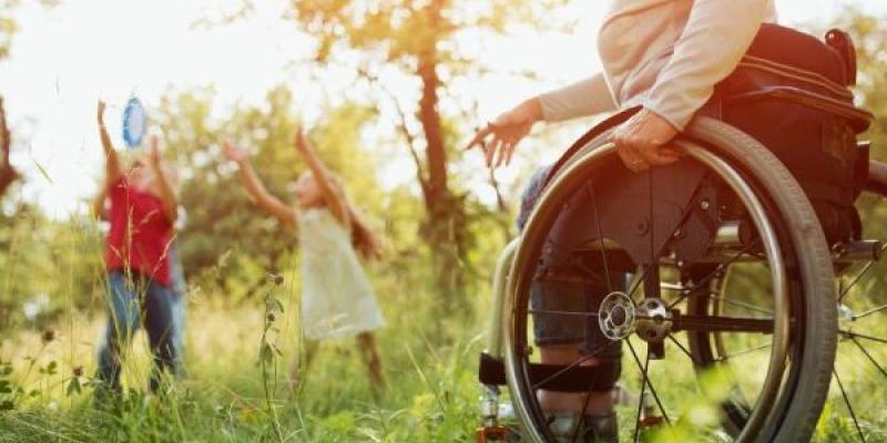 Una mujer en silla de ruedas en el campo con dos niños