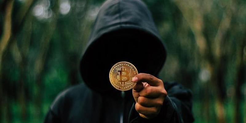 Un joven encapuchado sujeta un Bitcoin 