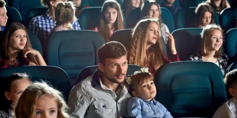 Varios padres y madres en el cine con sus hijos