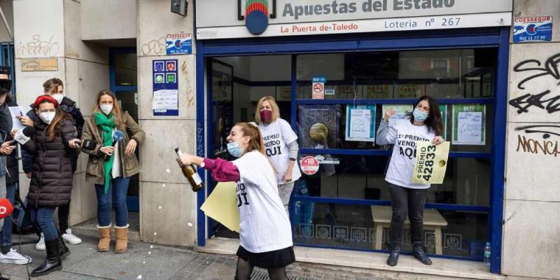 Gente en la puerta de una administración de lotería celebrando el premio