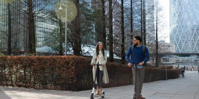 Fomentar la movilidad sostenible entre los empleados se ha convertido en una prioridad para las organizaciones que quieren contribuir a la sostenibilidad. Dos trabajadores en patinete