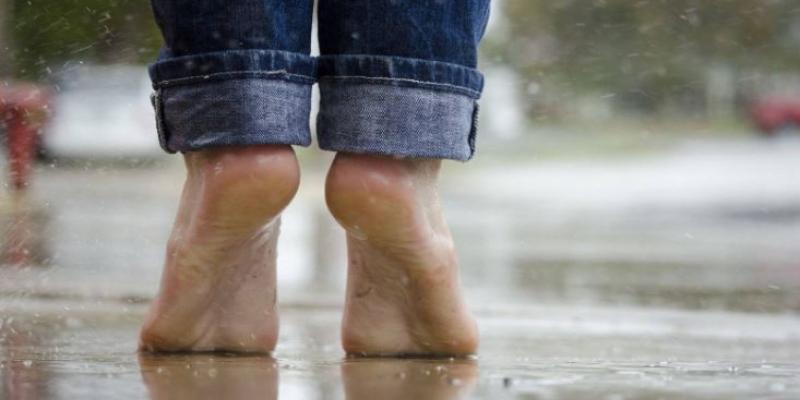 Imagen de dos pies descalzos pisando suelo mojado