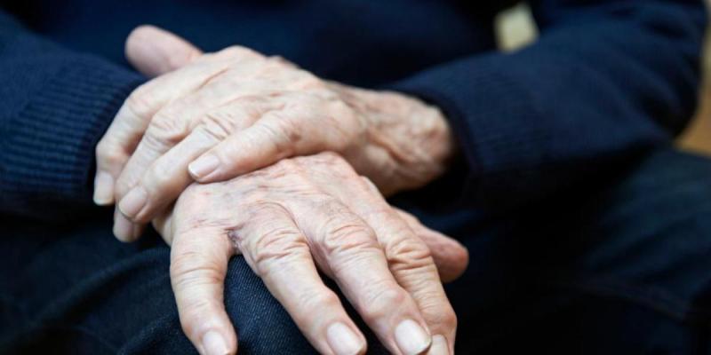 Un enfermo de Parkinson sostiene sus manos