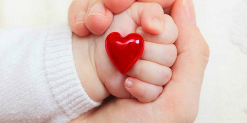 Mano de un bebé sosteniendo un corazón