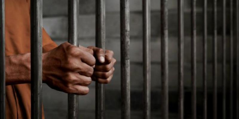 Un preso saca sus manos al otro lado de los barrotes de la celda 