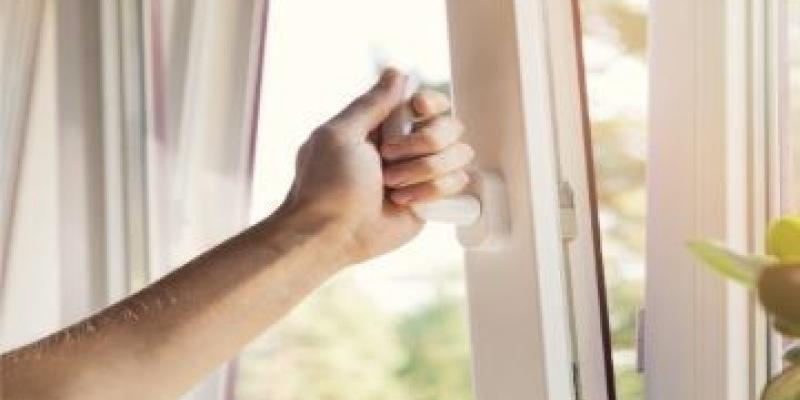 Covid-19 ventilar / Colegio de enfermería de Islas Baleares Una mano abre una ventana para ventilar la sala