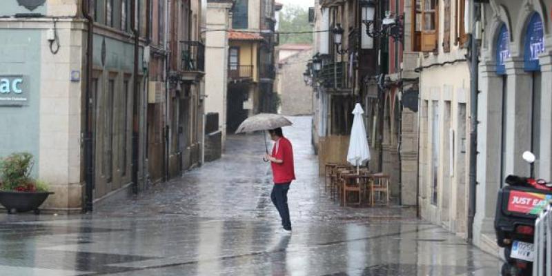 Señor paseando por la calle en Asturias bajo la lluvia de la DANA