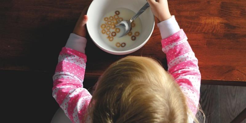 Niña desayuna plato de cereales