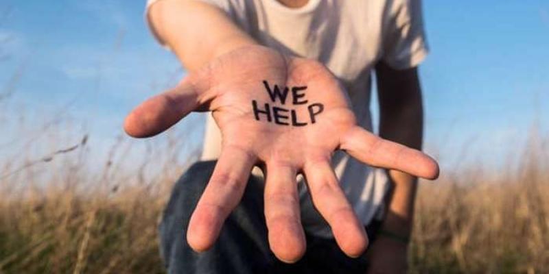 DÍA DEL VOLUNTARIADO INTERNACIONAL Mano con el mensaje 'We help' en inglés que significa, 'nosotros ayudamos'