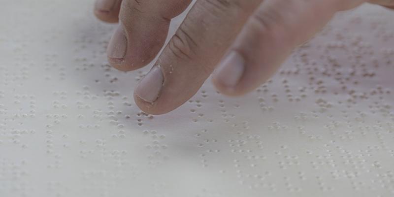 Manos de una persona con discapacidad visual leyendo en braille
