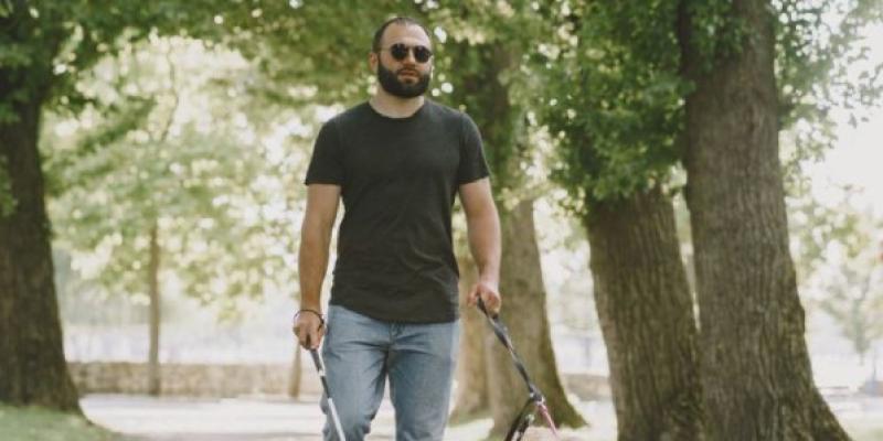 Una persona ciega camina por un parque con su perro guía | Foto de Servimedia Una persona ciega camina por un parque con su perro guía