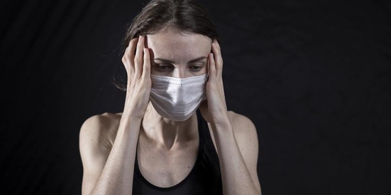 Mujer con mascarilla y dolores de cabeza