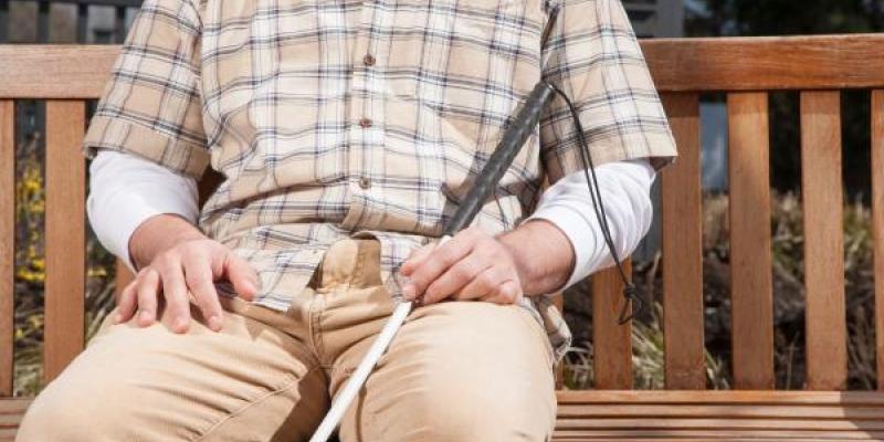 Una persona ciega descansa en un banco 