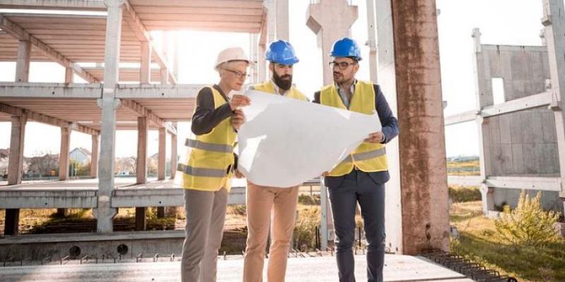 Tres arquitectos mirando unos planos