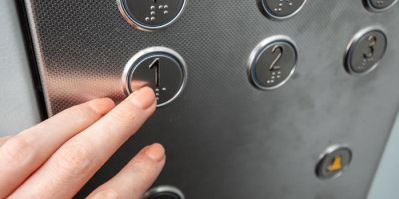 Braille | Foto de 123RF/markoaliaksandr Una mujer pulsa un botón accesible en un ascensor