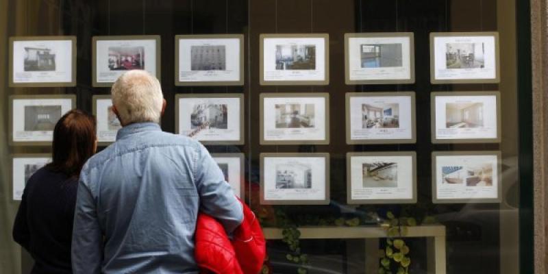 Dos personas mirando el escaparate de una inmobiliaria