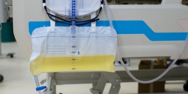 Una cama de hospital con una bolsa de orina colgando por un lado.