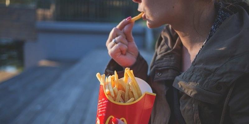 Persona comiendo patatas fritas de una conocida cadena de fast food