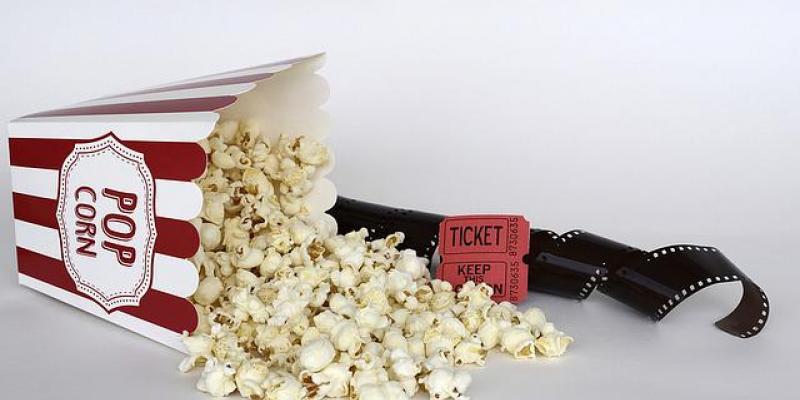 Un cono de palomitas junto a un ticket de cine 