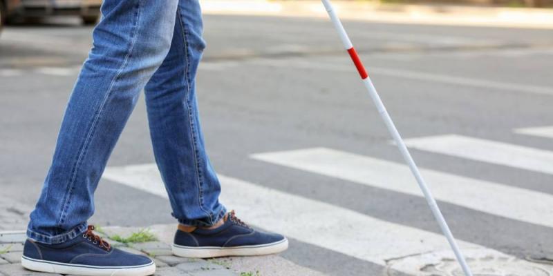 Piernas de una persona ciega utilizando un bastón