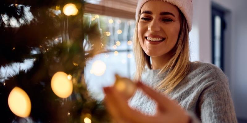 Chica colocando árbol de Navidad - Foto: Envato Elements Chica colocando árbol de Navidad
