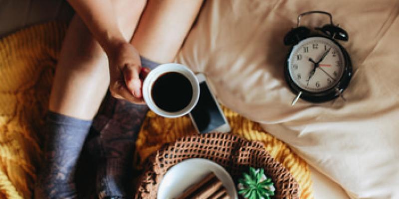 Imagen de una persona en la cama con un café/Envatoelements Hábitos matutinos para aumentar la longevidad