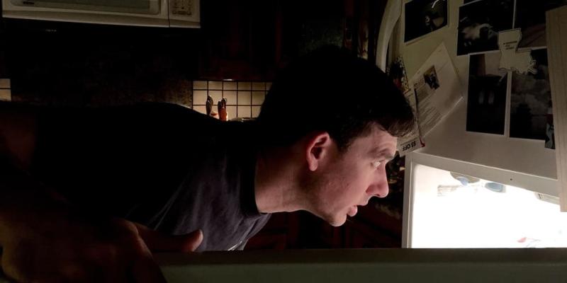 Imagen de un chico buscando en la nevera/envatoelements Razones por las que aparece el hambre