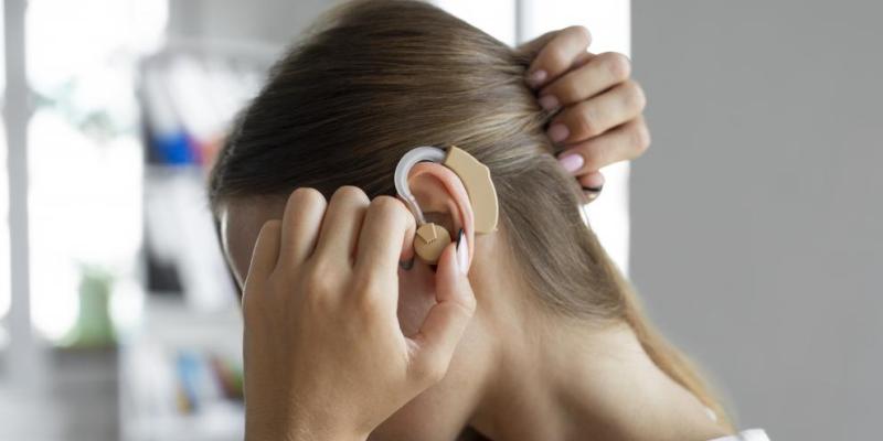 Implantes auditivos / Getty Images Chica colocándose un audífono