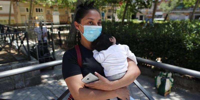 Una mujer con su bebé en brazos, acude a las puertas de la Parroquia Santa María Micaela para recibir una ayuda alimentaria. EUROPA PRESS