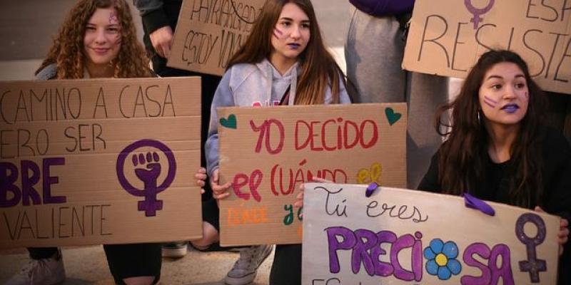 Tres jóvenes sujetan carteles en una manifestación feminista